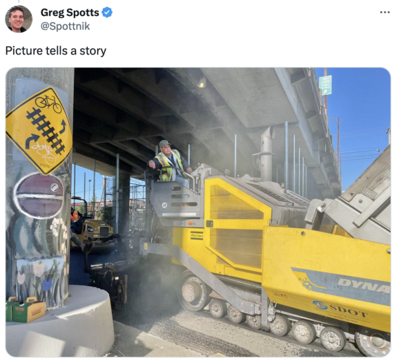 Screenshot of tweet by SDOT Director Greg Spotts with a photo of workers using a large paving machine under the Ballard Bridge. Text says: Picture tells a story.